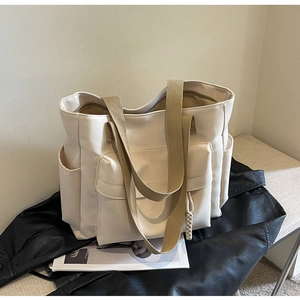 Detail of canvas tote bag showing front flap pocket and side storage compartments