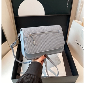 Detail of the woven texture flap and silver metal zipper on light blue crossbody bag