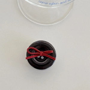 Close-up of a glossy black round phone grip with a delicate red velvet ribbon bow