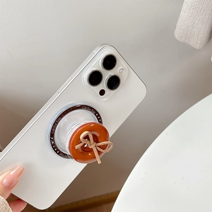 Close-up of caramel magnetic phone grip with beige bow on a white smartphone