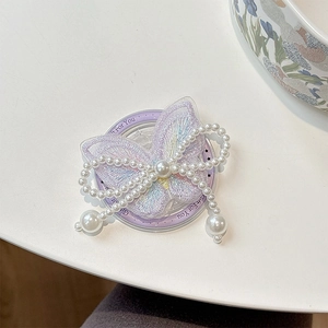 Detail of magnetic phone grip featuring purple butterfly embroidery and pearl bow accent