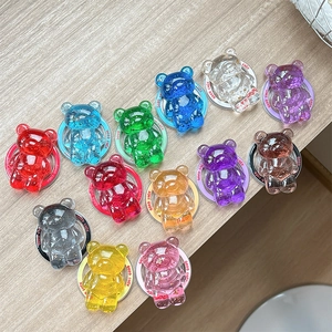 Colorful resin bear phone holders with Good Luck base on a wooden desk surface