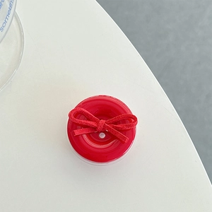 Detail of red circular phone grip featuring a vibrant suede texture bow on smooth surface
