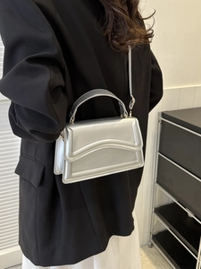 Chic silver metallic handbag shown on a model with a black blazer and white skirt