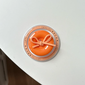 Close-up of orange donut phone grip with a velvet bow on a Gift For You card stand