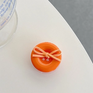 Close-up of an orange button-shaped phone grip featuring a cute bow decoration