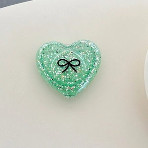 Detail of green glitter heart phone grip with a black bow print and sparkling sequins