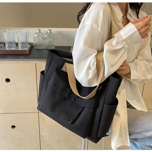 Close-up of large canvas tote bag with contrast khaki strap and functional front pocket