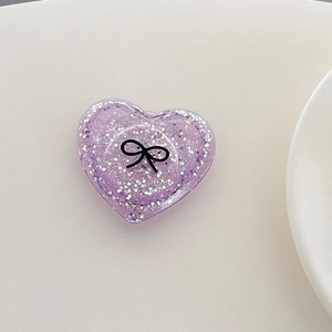 Macro shot of purple heart-shaped phone grip with silver glitter and black bow design