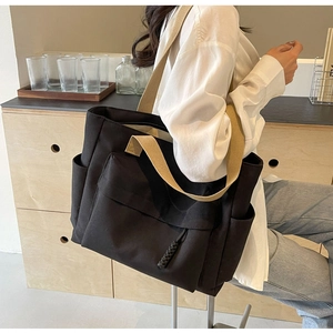 Detailed view of black canvas tote bag with multi-pocket design and wide shoulder strap