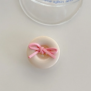 Macro shot of minimalist cream resin button phone grip with a soft pink velvet bow detail