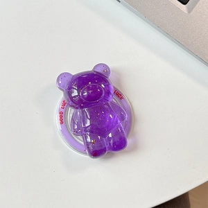 Detail of purple bear phone grip with gold flakes and Good Luck text on white desk