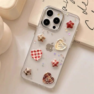 Detail of glitter heart and star button ornaments on a plaid iPhone case over a book