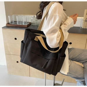 Detail of high-capacity black canvas tote bag with multi-pocket design and woven straps