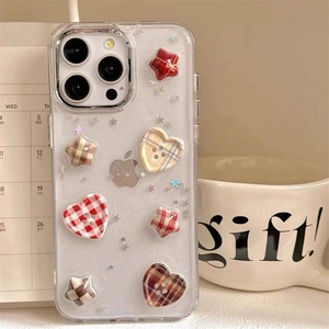 Detail of clear iPhone case with glitter finish, heart and star pattern buttons on table