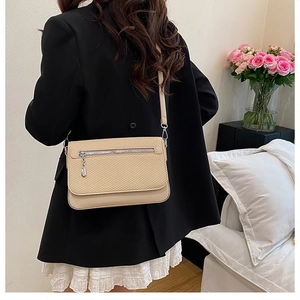 Fashionable beige crossbody bag with woven texture on a model in a cozy home setting