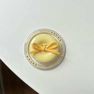 Close-up of yellow button phone grip with suede bow in a Gift For You package
