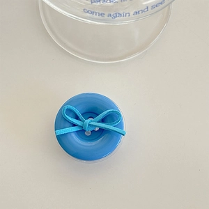 Close-up of blue button phone socket with a matte bow tie on white tabletop