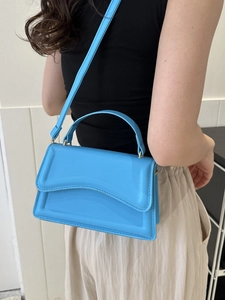 Side view of electric blue leather handbag with wave edge flap and gold hardware