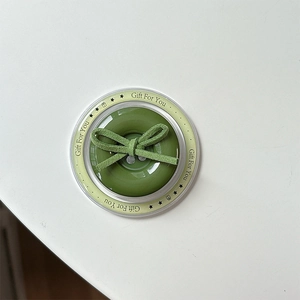 Detail of green button phone grip with bow tie in branded Gift For You packaging