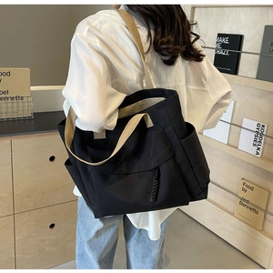Detail of canvas tote bag showing side storage pocket and contrast shoulder straps