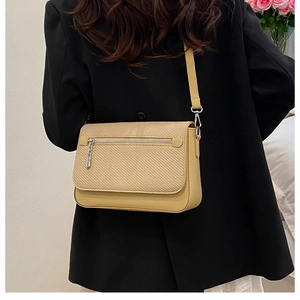 Detail of elegant beige crossbody bag showing weave texture and smooth finish on model