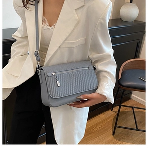 Adjustable silver metal buckle and textured leather strap on a blue crossbody bag