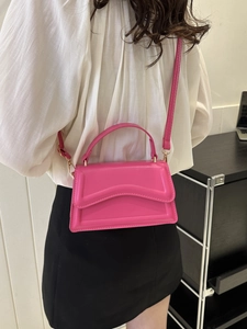 Detail of rose pink crossbody bag featuring wave pattern flap and matching top handle