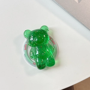 Macro view of a green resin bear phone stand with gold foil flakes and Good Luck text