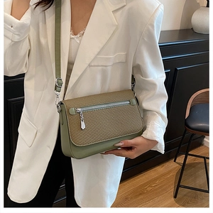 Detail of sage green crossbody bag with textured flap on white suit model