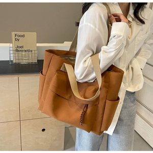 Detail of caramel canvas tote bag featuring front flap pocket and woven zipper puller