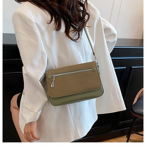 Detail of olive green leather and woven crossbody bag shown on a white blazer