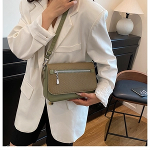 Detail of crossbody bag featuring green leather trim and fabric texture on a model