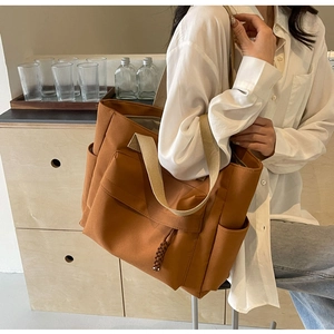 Close-up of a large brown canvas tote bag with contrast straps in a lifestyle setting