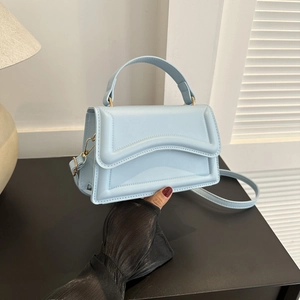 Detail of light blue structured handbag with layered design and elegant gold hardware