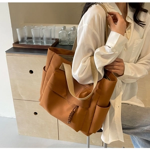 Detailed side view of caramel canvas tote bag showing the large pocket and strap