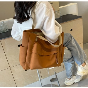 Detail view of large terracotta canvas crossbody bag with functional flap pocket and side pouch