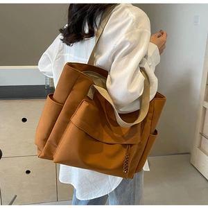 Brown canvas tote bag detail showing large front flap pocket and side compartment