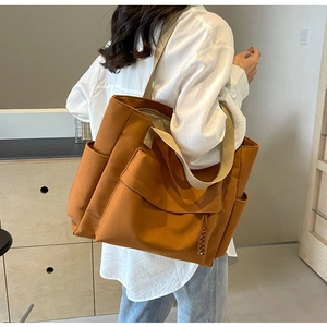 Caramel brown canvas tote bag with multi-pocket details shown on a model for daily use
