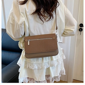 Brown woven texture crossbody bag detail with silver zipper and smooth leather finish