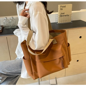 Brown canvas tote bag with multi-pocket design shown on model in minimalist interior