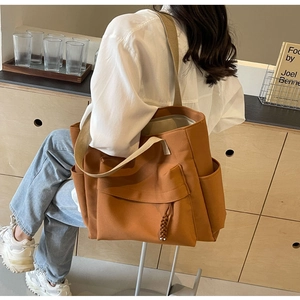 Caramel canvas tote bag with front pocket and shoulder strap shown on a model