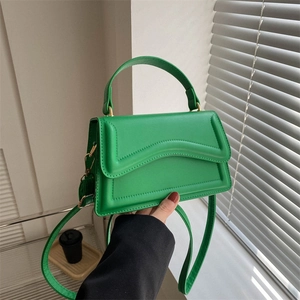 Modern bright green leather handbag with wavy stitching and golden metal hardware details