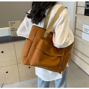 Back view of a model wearing the large caramel canvas tote bag with wide straps