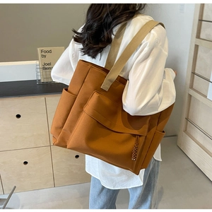 Detailed shot of a large caramel canvas tote bag with front pocket and thick shoulder straps