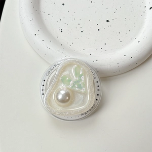 Detail of heart-shaped phone grip with faux pearl and aurora crystal on ceramic tray