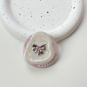 Detail shot of pearlescent resin phone grip with silver bow and pink heart gemstone