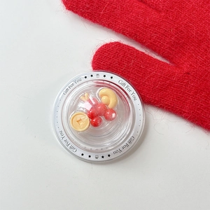Close-up of decorative red charm and gold coin in a gift box with a red glove