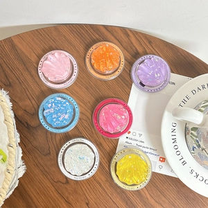Colorful seashell phone grip stand with glitter and Gift For You text on wooden surface