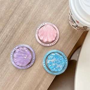 Set of three colorful glitter shell-shaped phone sockets on a light wooden background